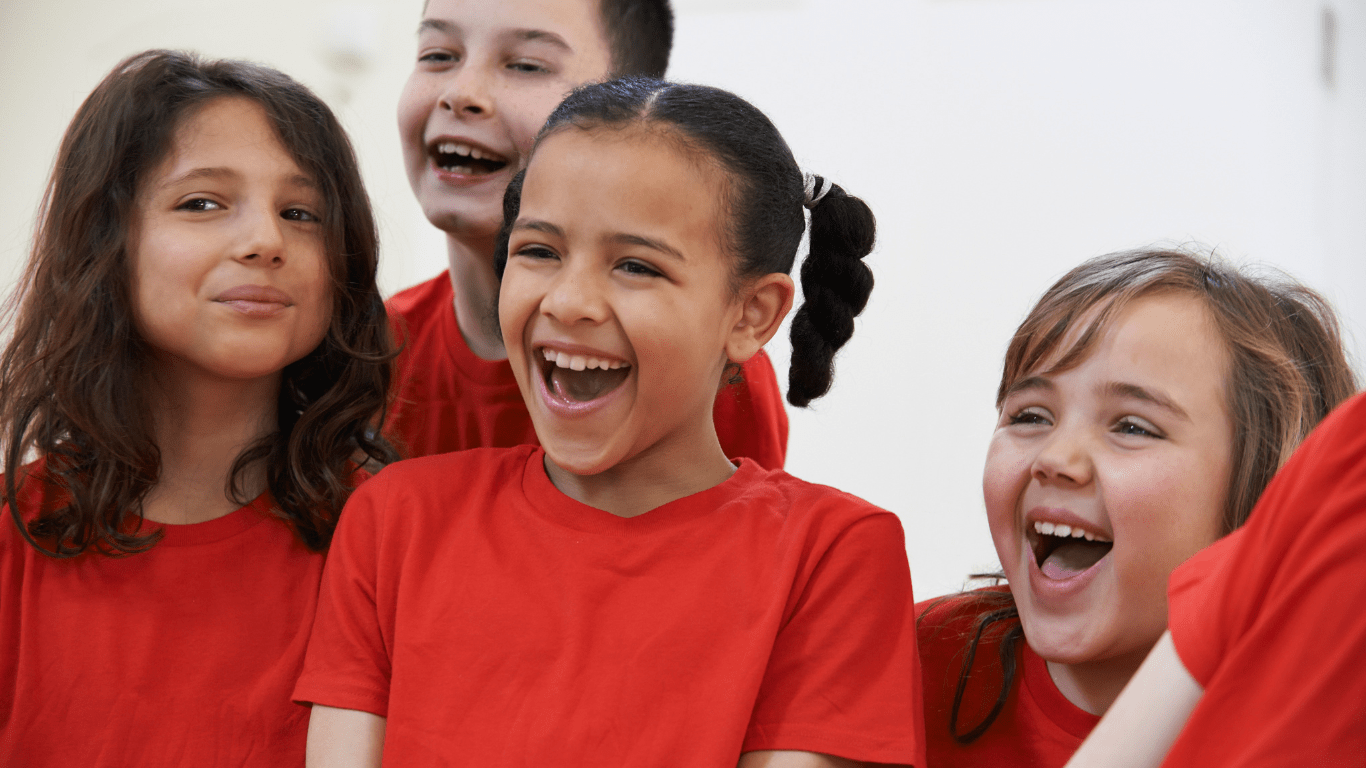 A group of children wearing red shirts, joyfully laughing together in a playful setting