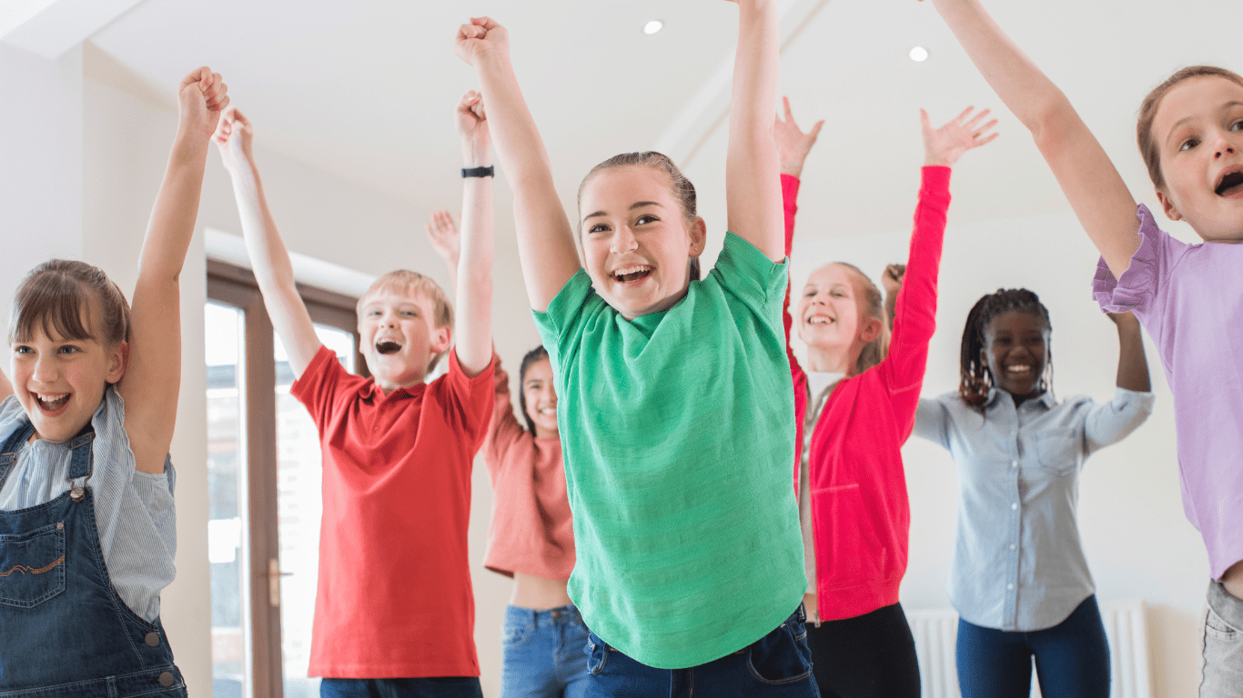 A group of children enthusiastically raising their hands in the air, expressing excitement and engagement